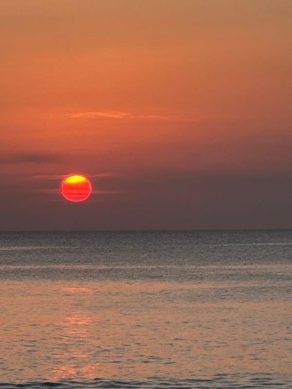 Busy Bali beach at golden hour: volleyball, surf, and sunset crowds