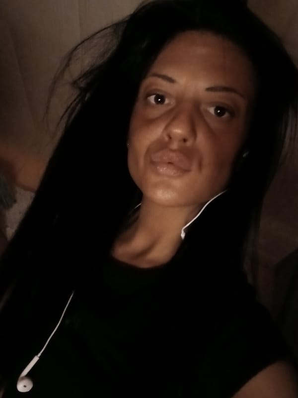 Woman photographs herself indoors with baby bassinet nearby