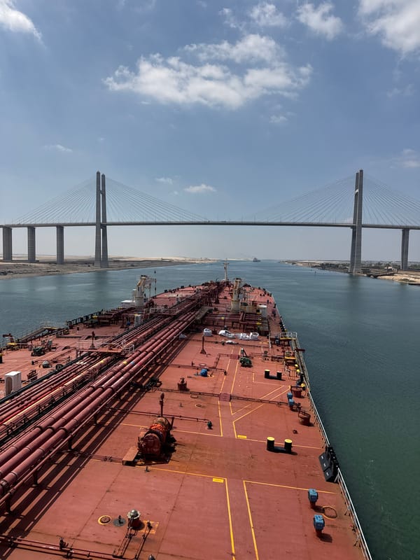 Red cargo ship transits the Suez Canal beneath a cable-stayed bridge