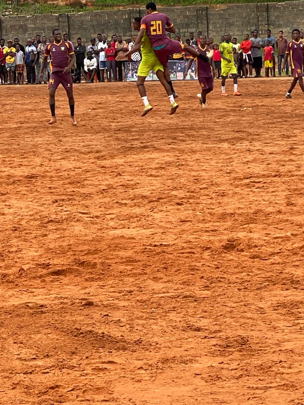 Soccer teams clash on dirt field as spectators gather
