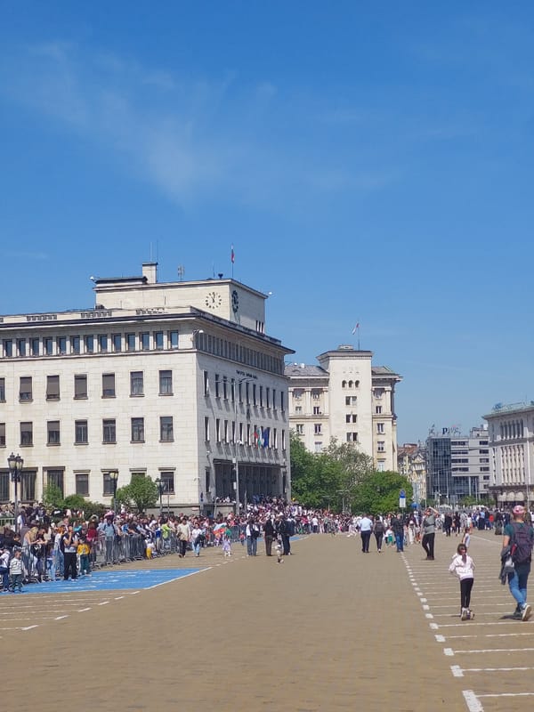 Crowd gathers behind fence near urban clock tower building