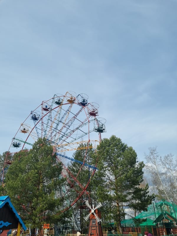 Children explore padlock fence near Ferris wheel on sunny morning