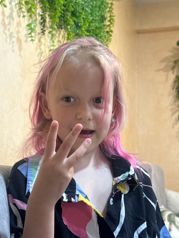 Child with pink-streaked hair plays indoors during evening hours