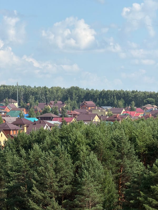 Russian suburb: forest canopy, apartment blocks, and delivery trucks