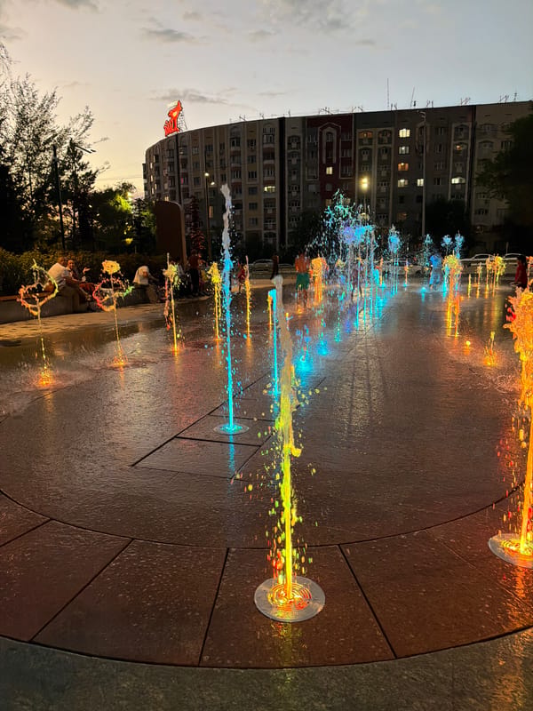 Almaty at dusk: lit fountains and busy highway traffic