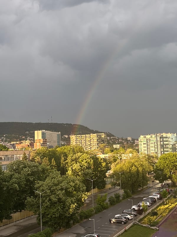 Urban skyline observed during cloudy afternoon with rainbow sighting