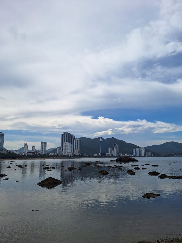 Nha Trang's rocky shoreline at low tide, city skyline in the background
