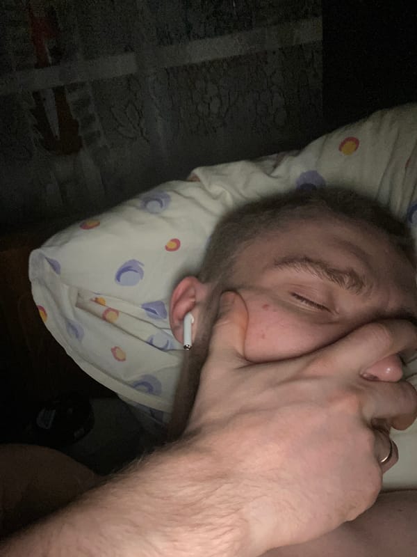 Man rests on bed in dimly lit room in Russia