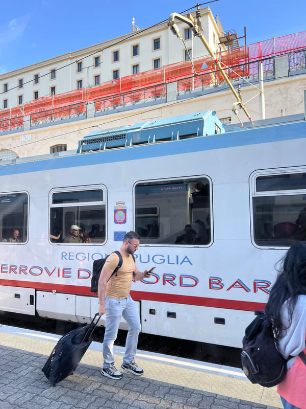 Man stands on sunny train platform in Bari, Italy