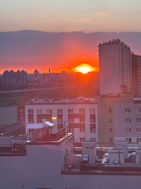 Sunset documented over Vsevolozhsk apartment buildings, cat observed indoors