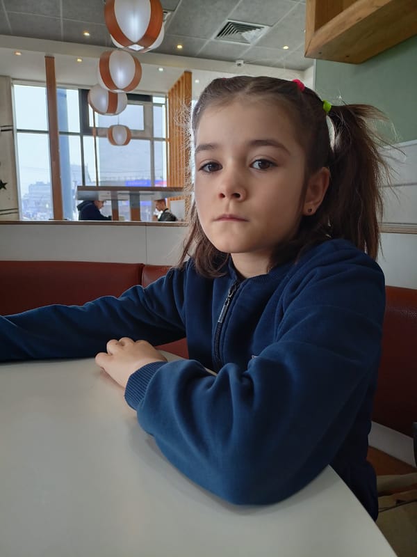 Girl in pigtails sits at indoor table