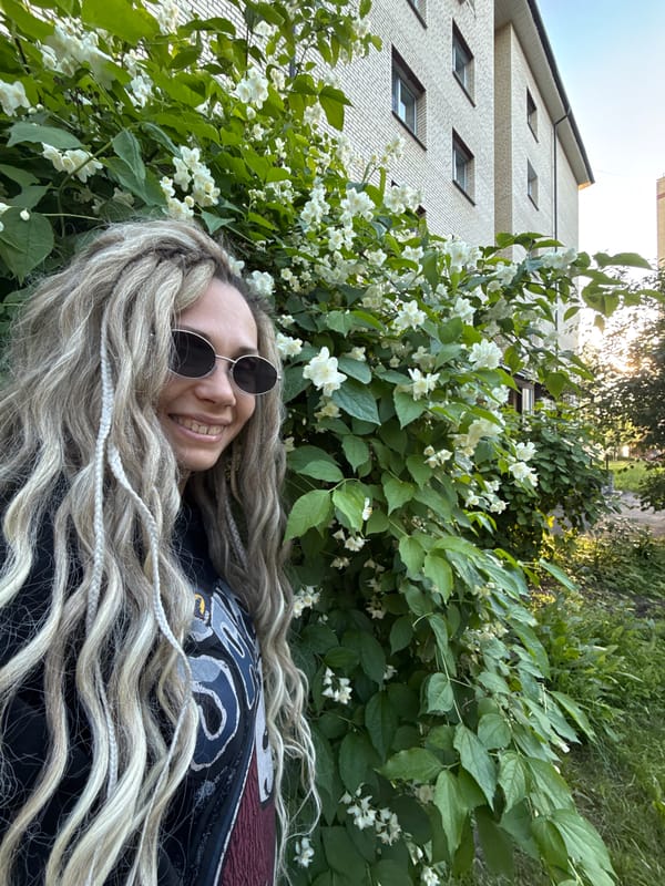 Woman poses by flowering jasmine bush in Rusanovo