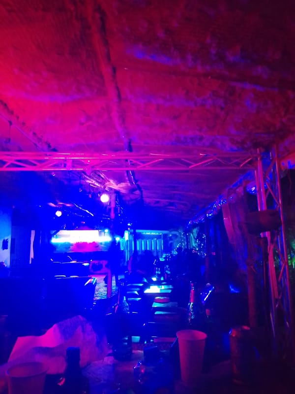 Neon-lit nighttime social gathering documented in Yelwa, Nigeria venue