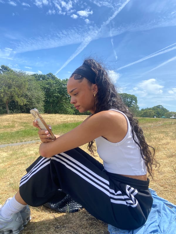 Woman crouches in London park examining ground on sunny day