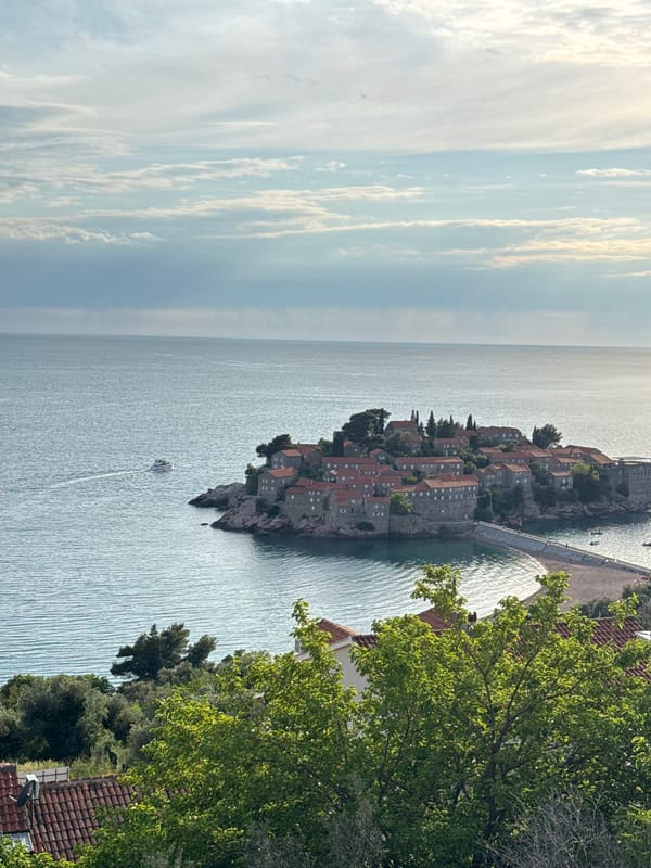 Tourists photograph scenic Sveti Stefan island resort Montenegro afternoon