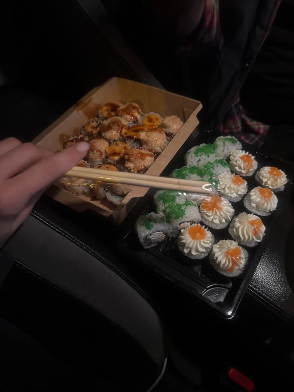 Person enjoys takeout sushi meal in vehicle, Tbilisi