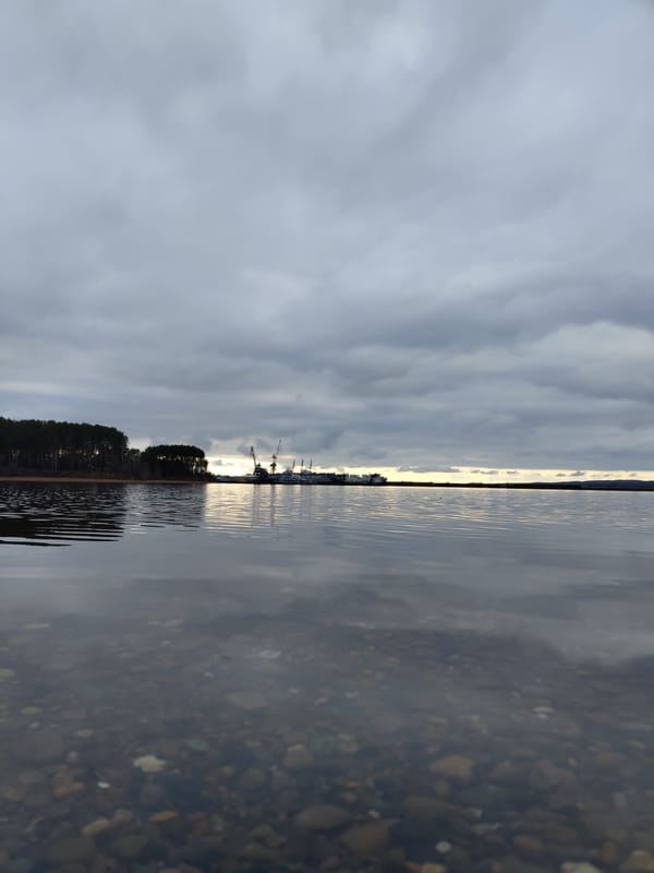 Child visits waterfront on overcast afternoon in Chaikovsky, Russia