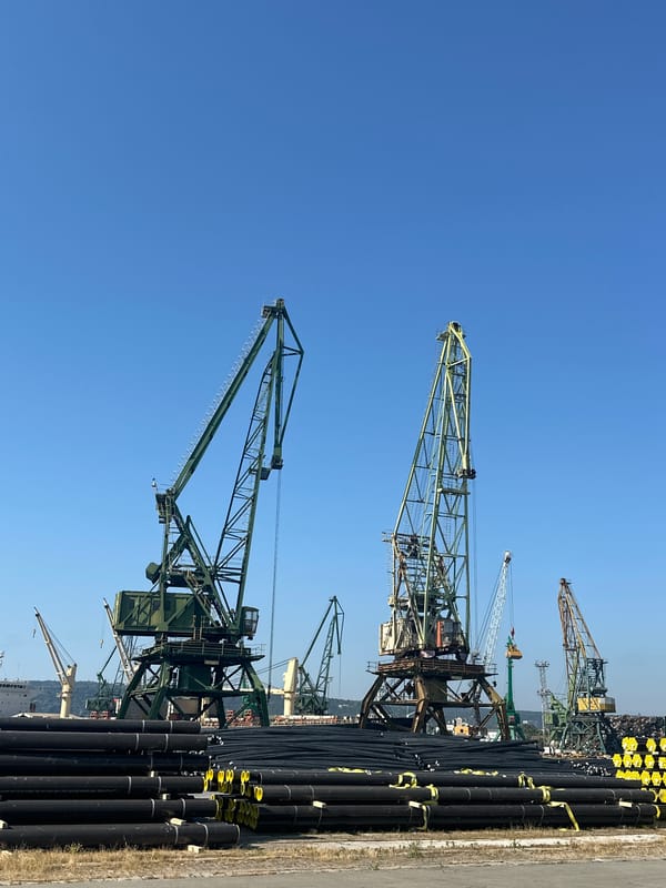 Industrial port stacked with pipes and cranes on a clear day