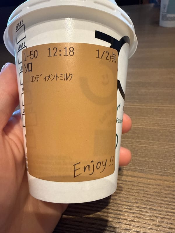Person holds labeled Japanese coffee cup in Shibuya