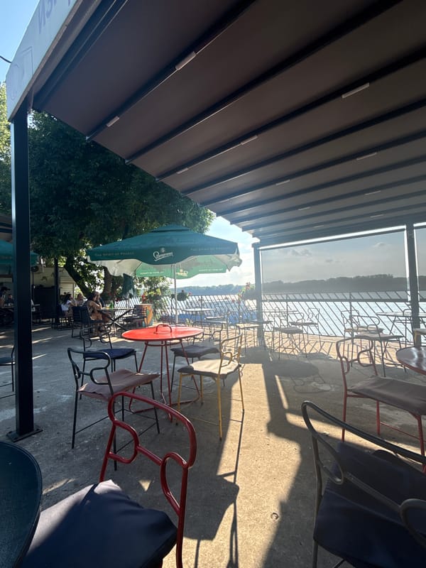 Outdoor festival with food, a stage, and a riverside backdrop