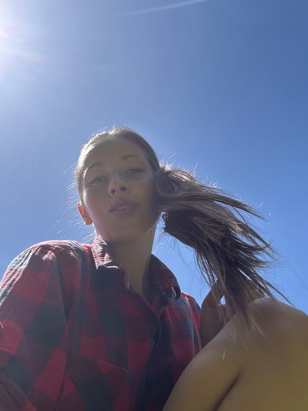 Woman in plaid shirt photographed against blue sky in Mengwi