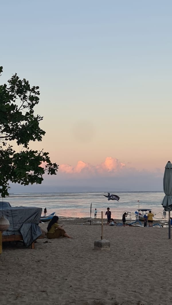 Denpasar beach at golden hour: boats, kites, and a full moon