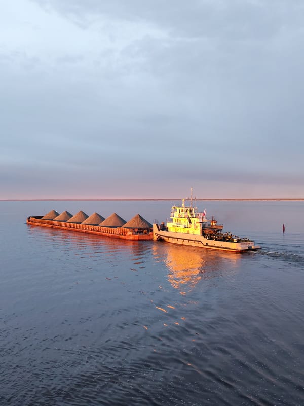 Tugboat pushes gravel-laden barge through Russian waterway