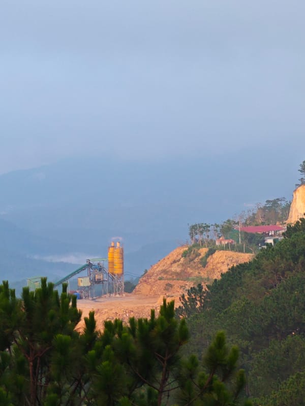 Greenhouses and concrete plant share a Vietnamese hillside valley