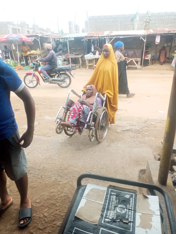 Woman helps elderly person navigate busy Nigerian market