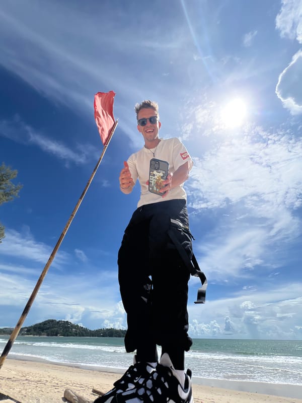 Lazy beach hangout under a red flag with watermelon and waves