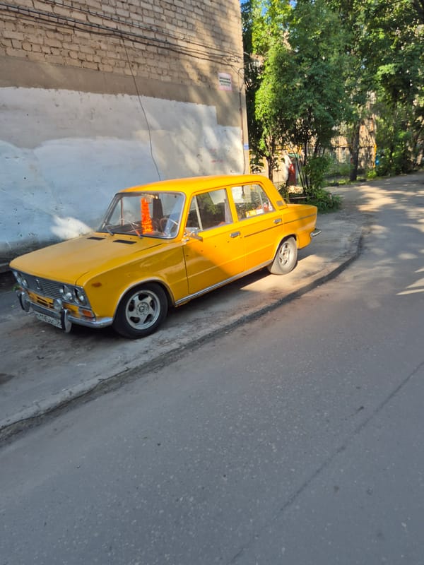 Urban street scene with yellow car, weathered buildings, jasmine flowers
