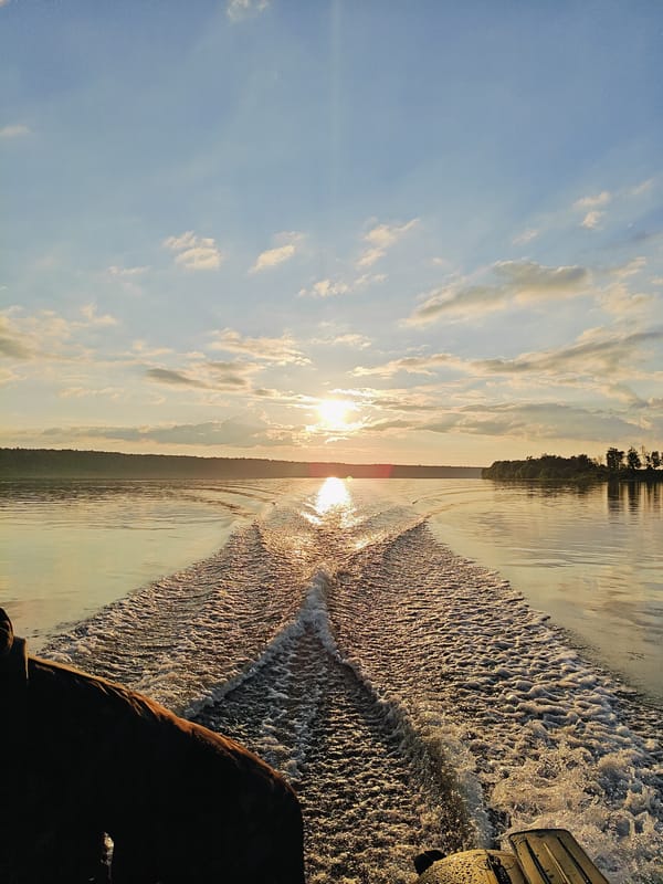 Boat on golden evening water, forested industrial shore, Chernushka