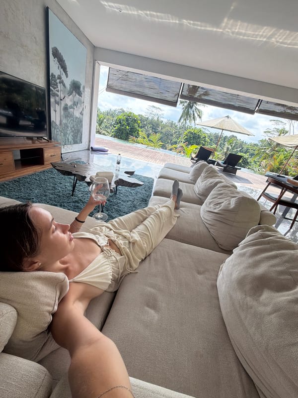Woman relaxes with wine glass on sofa in Petulu home