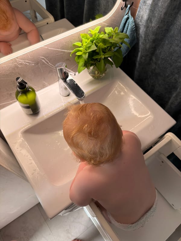 Toddler plays with water at bathroom sink in Germany