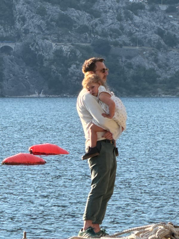 Father holds child on pier in Perast, Montenegro