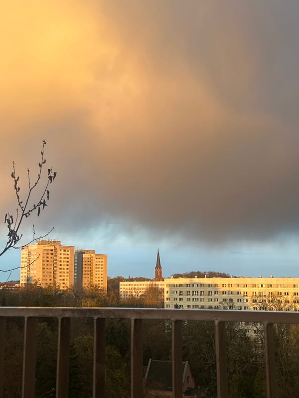Person watches Berlin sunset from balcony overlook