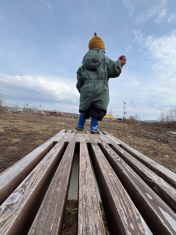 Child plays on bench amid spring thaw in Павловка