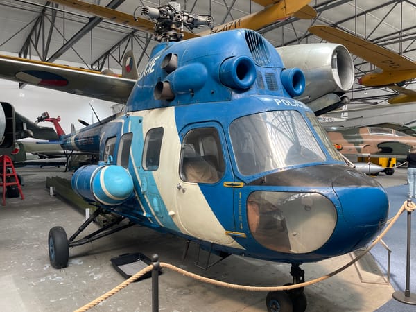 Inside a military aviation museum with aircraft, drones, and artillery