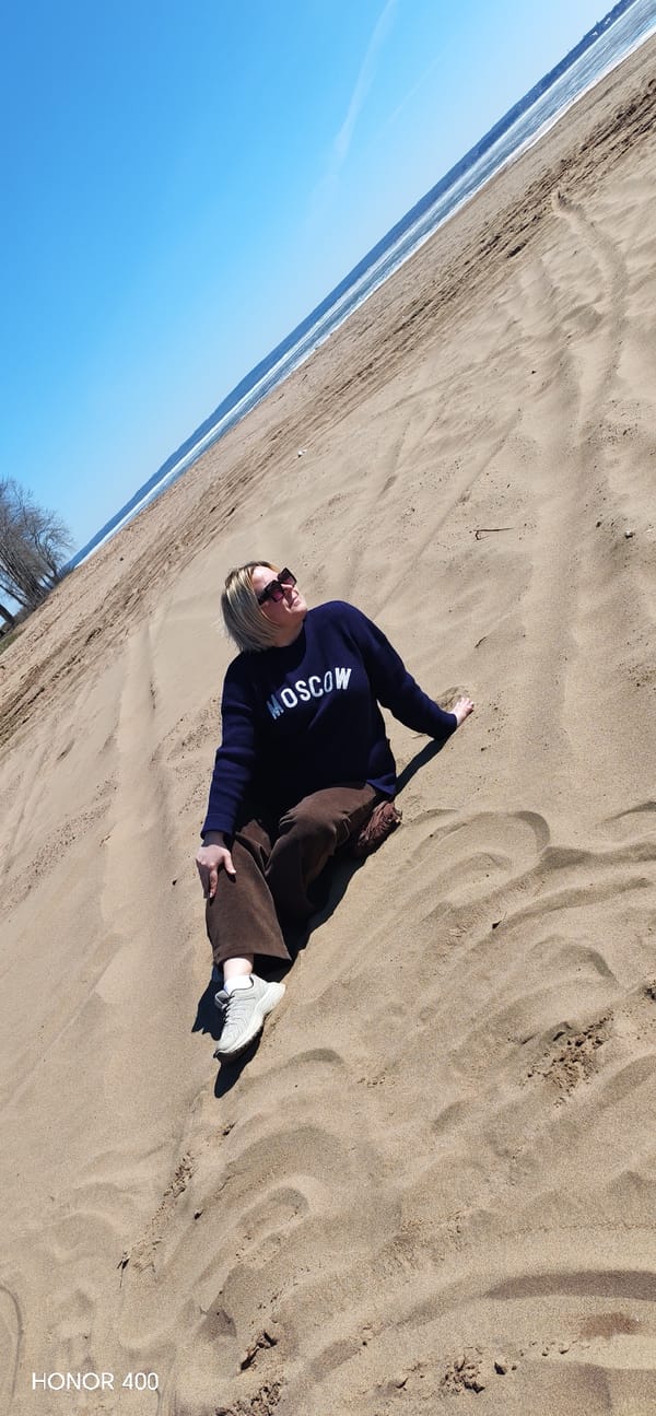Woman in Moscow sweatshirt visits sandy beach in Noviy, Russia