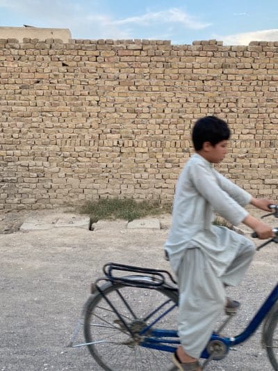 Daily life unfolds on Kandahar street near brick wall