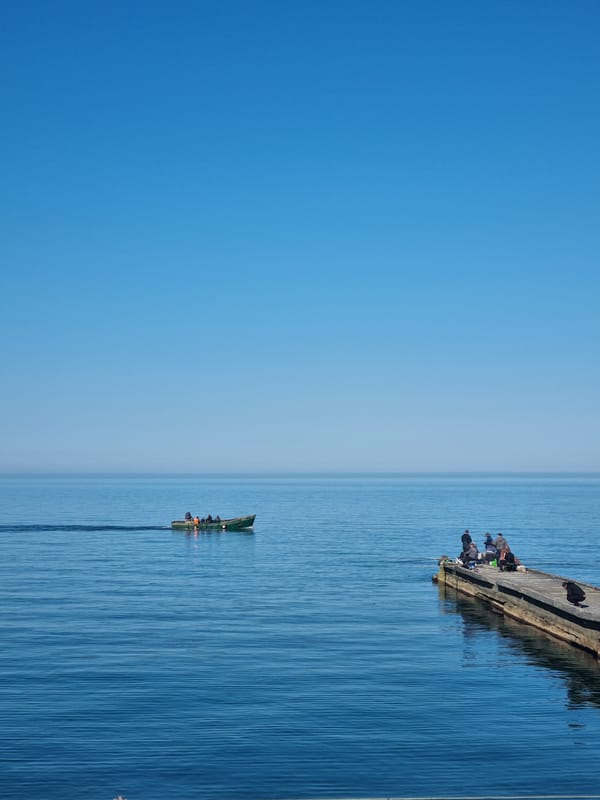 People gather on concrete pier in Khostinskiy under clear skies