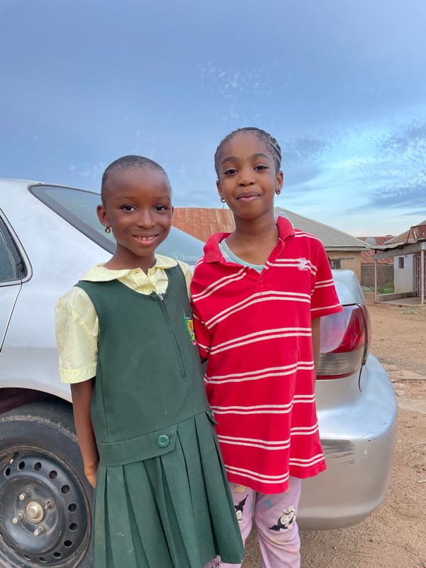 Nigerian school children pose with silver car after classes