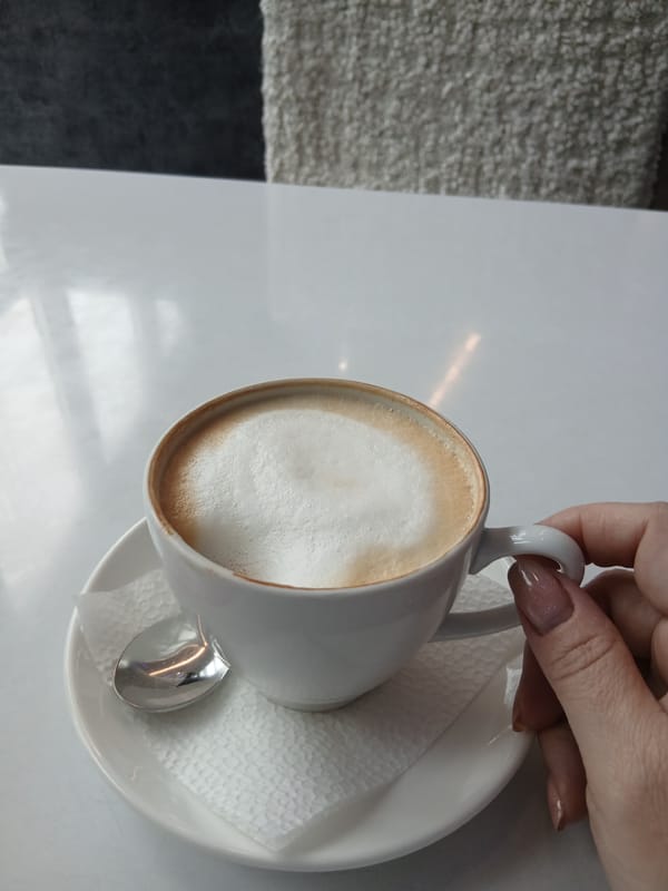 Woman drinks latte from white cup in striped shirt