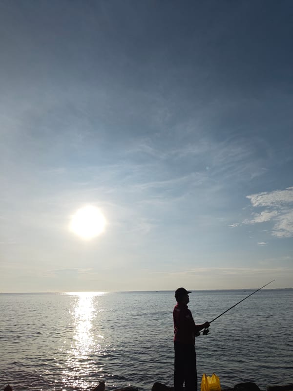 Fisherman and cat share quiet dawn moment on Indonesian shore