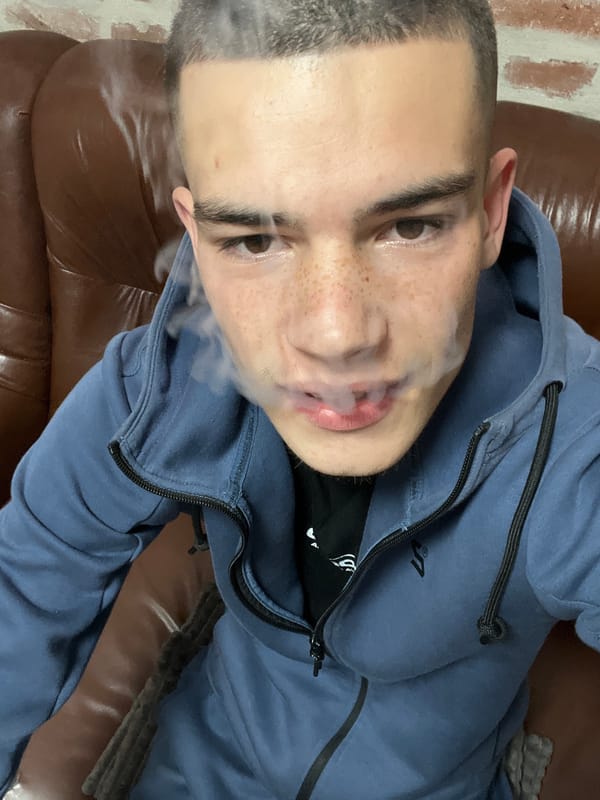 Young man smoking on couch indoors in Plovdiv