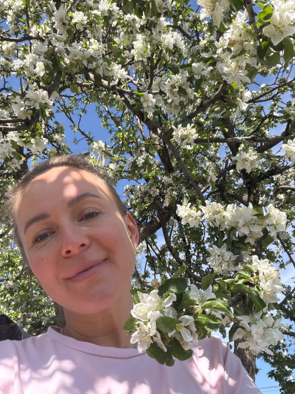 Woman photographs blooming trees in Chaikovsky garden scene
