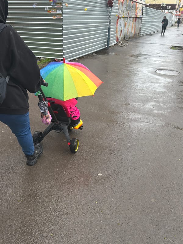 Parent walks baby in rain with rainbow umbrella, Rostov-on-Don