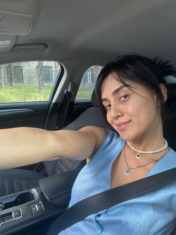 Driver selfies in Tbilisi traffic, light blue top and pearl necklace