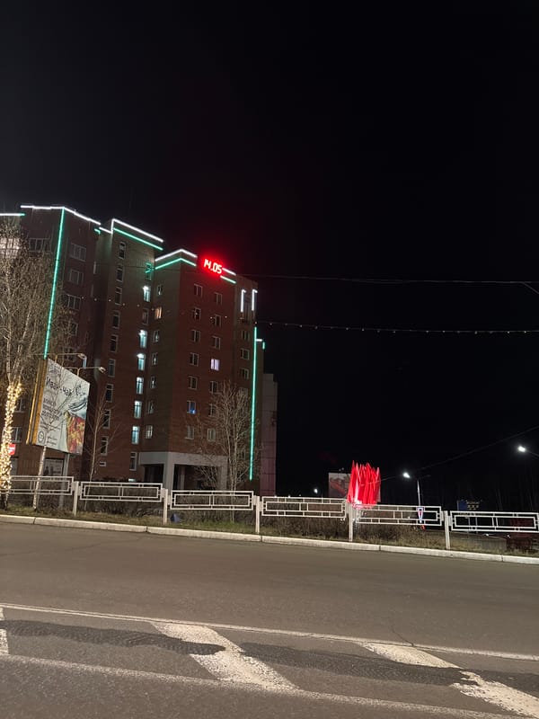 Green-lit building displays digital clock in Ust-Ilimsk nightscape