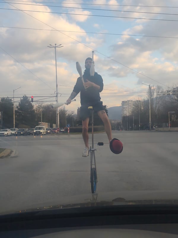 Street performer unicycles in Sofia intersection near Vitosha Mountain